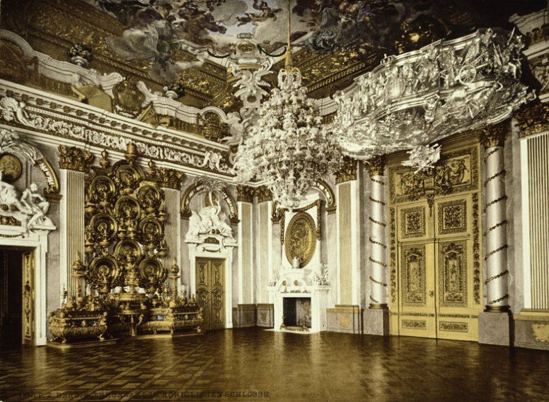 A large ornate room with gold ceiling and ornate chandelier Description automatically generated